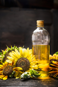 bottle of Sunflower oil with fresh blooming on dark wooden background