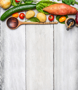 Fresh organic vegetables ingredients and wooden spoon on rustic wooden background, top view. Healthy eating concept.