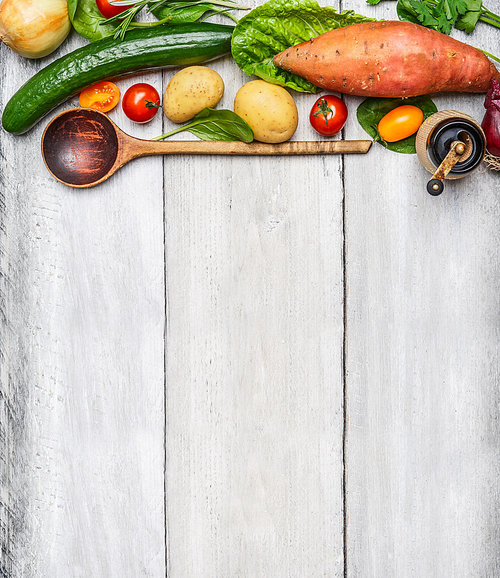 Fresh organic vegetables ingredients and wooden spoon on rustic wooden background, top view. Healthy eating concept.