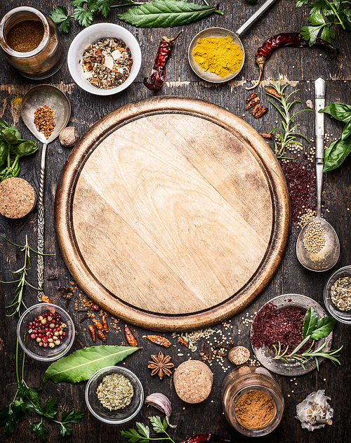 variety of herbs and spices  around empty cutting board on rustic wooden background, top view.Creative and national cuisine  and cooking concept.