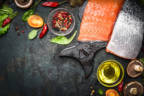 Salmon fillet with delicious ingredients for cooking on dark rustic wooden background, top view, frame. Healthy, diet or vegetarian food concept.