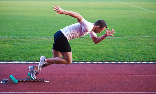 Sprinter leaving starting blocks on the running track. Explosive start.