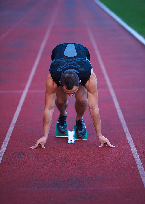 Sprinter leaving starting blocks on the running track. Explosive start.