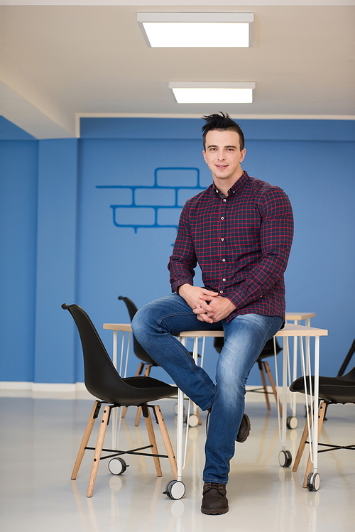 portrait of young business man in casual clothes sitting on table at  new startup office space