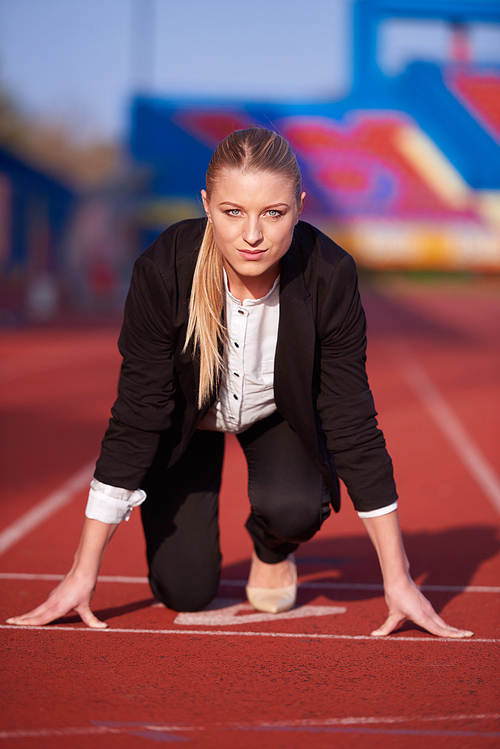 business woman in start position ready to run and sprint on athletics racing track