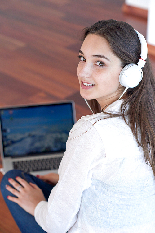 beautiful young woman relax and work on laptop computer modern  home office while listening musin on white headphones