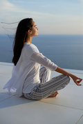 young woman practice yoga meditaion on sunset with ocean view in background