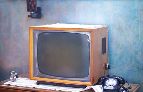 Vintage retro look living room detail. Television, telephone and clock on wooden old table