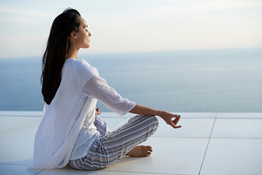 young woman practice yoga meditaion on  with ocean view in background