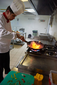 chef in hotel kitchen prepare   food with fire