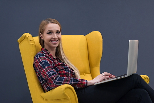 startup business, woman  working on laptop computer at modern office and sitting on creative yellow armchair