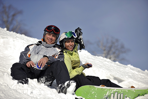 young snowboarders couple relaxing and enjoy on sunny winter day on fresh snow
