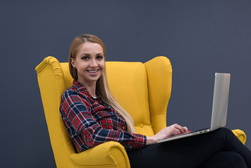 startup business, woman  working on laptop computer at modern office and sitting on creative yellow armchair