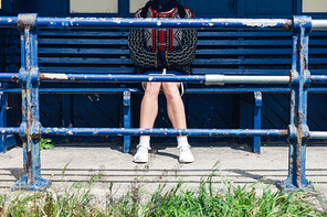 A young woman is sitting at a bus stop on the beach