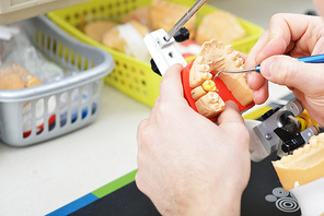 dental technician working on false teeth. table with dental tools.