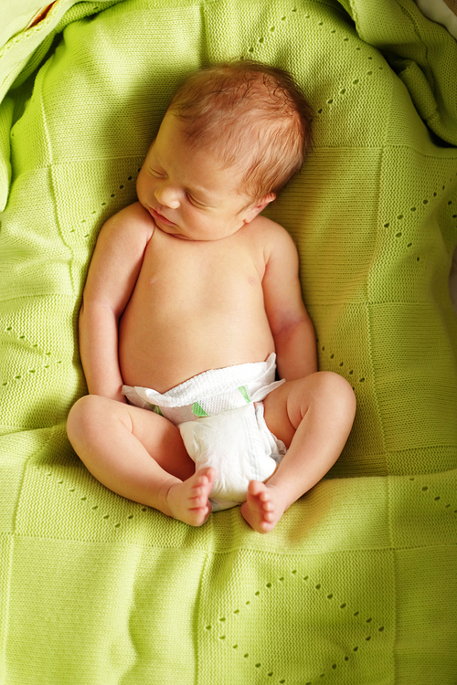 One week old newborn baby in bed