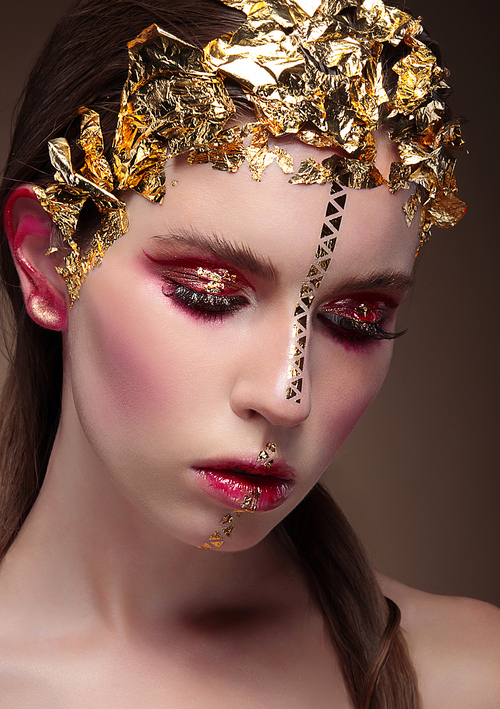 Closeup portrait of  woman with creative makeup  and gold foil.