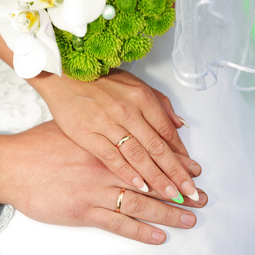 Hands with wedding rings and bouquet from white orchid