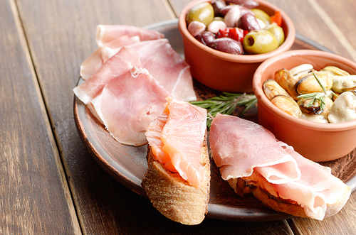Tapas of salmon, mussels, jamon and olives on ceramic plate