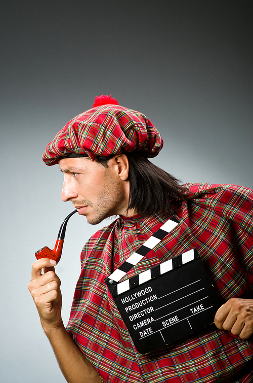 Funny scotsman with movie board and smoking pipe