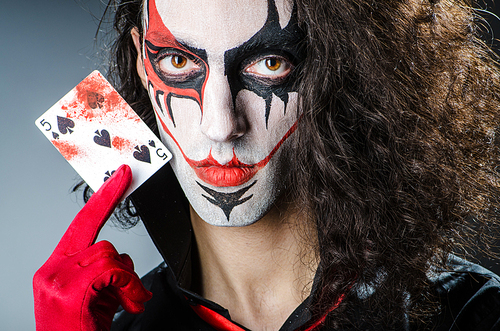Evil clown with cards in dark room