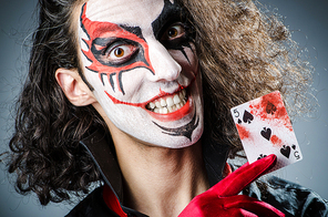 Evil clown with cards in dark room