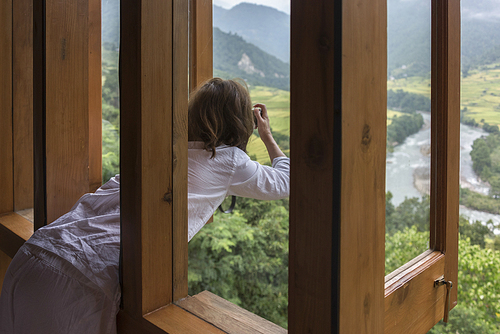 Woman taking a picture through window at Uma Punakha Hotel, Punakha, Bhutan