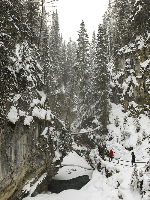 Tourists walking in snow covered trail in canyon, Johnston Canyon, Banff National Park, Alberta, Canada