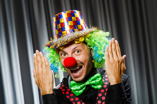 Funny clown in humorous concept against curtain