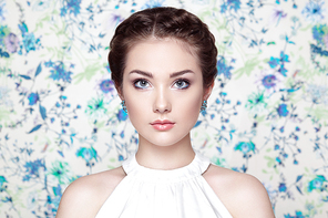 Portrait of young beautiful woman on a background of flowers. Fashion photo. Jewelry and hairstyle. Perfect makeup