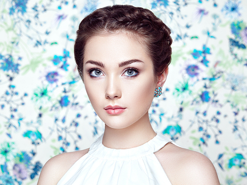 Portrait of young beautiful woman on a background of flowers. Fashion photo. Jewelry and hairstyle. Perfect makeup