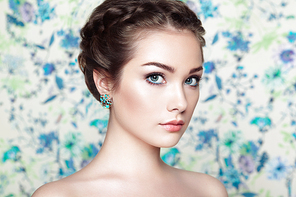 Portrait of young beautiful woman on a background of flowers. Fashion photo. Jewelry and hairstyle. Perfect makeup
