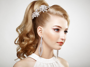 Fashion portrait of young beautiful woman with jewelry and elegant hairstyle. Blonde girl with long wavy hai. Perfect make-up.  Beauty style woman with diamond accessories