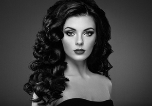 Brunette woman with curly hairstyle. Beautiful girl with long wavy hair. Perfect makeup. Fashion photo. Black and White