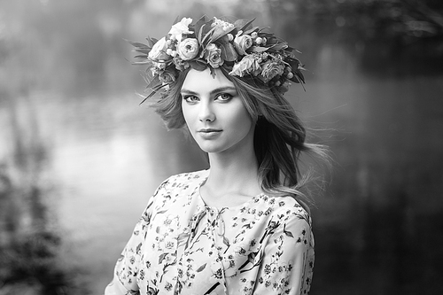 Beautiful blonde woman with flower wreath on her head. Beauty girl with flowers hairstyle. Girl in a summer forest. Fashion photo. Black and White