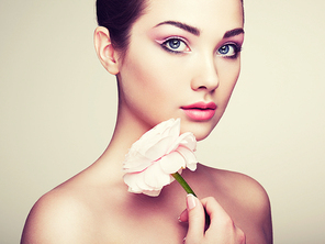 Portrait of beautiful young woman with flowers. Brunette woman with luxury makeup. Perfect skin. Eyelashes. Cosmetic eyeshadow