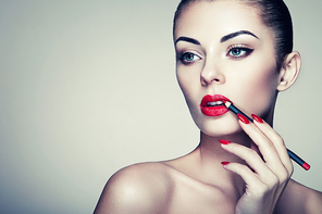 Beautiful woman paints lips with lipstick. Beautiful woman face. Makeup detail. Beauty girl with perfect skin. Red lips and nails manicure