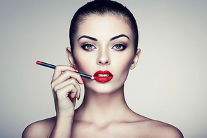 Beautiful woman paints lips with lipstick. Beautiful woman face. Makeup detail. Beauty girl with perfect skin