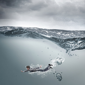 Young businessman in suit swimming in stormy waters