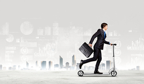 Image of young businessman in black suit riding scooter