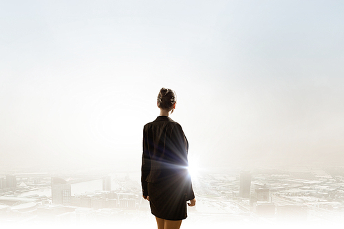 Rear view of businesswoman looking at sunset above city