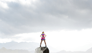 Young girl in multicolored bright dress on rock top