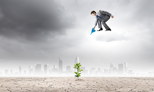 Young businessman standing on cloud and watering sprout