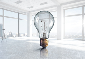 Glass light bulb against room with large window looking on city