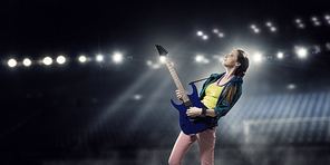 Young attractive rock girl with electric guitar on stage