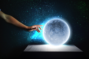 Close up of human hand touching blue glowing moon