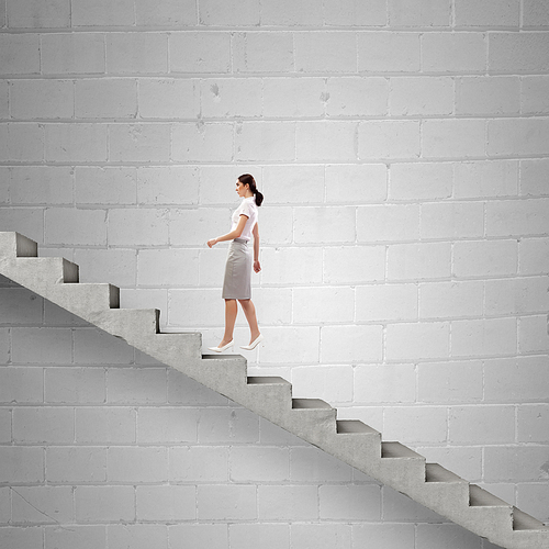 Young businesswoman walking up on staircase representing success concept