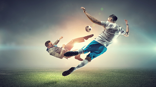 Young businessman in suit playing football with players outdoors
