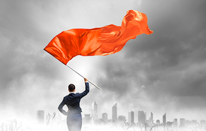 Young determined businesswoman with red flag in hands