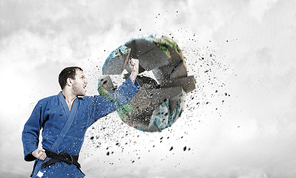 Determined karate man breaking Earth planet. Elements of this image are furnished by NASA